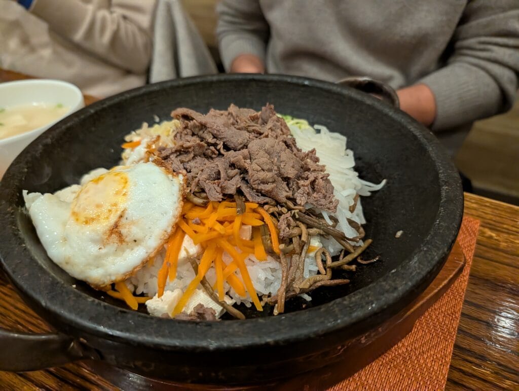 Dolsot Bibimbap served in a hot stone bowl at DuBu, topped with bulgogi beef, a fried egg, carrots, bean sprouts, and other vegetables.