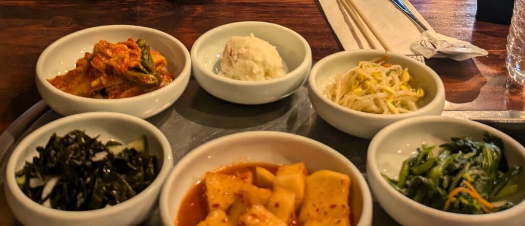Assorted Korean Banchan (side dishes) served at Yechon Korean Restaurant, including kimchi, potato salad, bean sprouts, seaweed salad, and radish kimchi.
