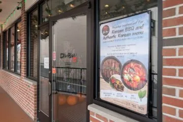 Entrance of DuBu Korean Restaurant in Elkins Park, PA featuring a window poster for Authentic Korean BBQ and Soondubu Jjigae.
